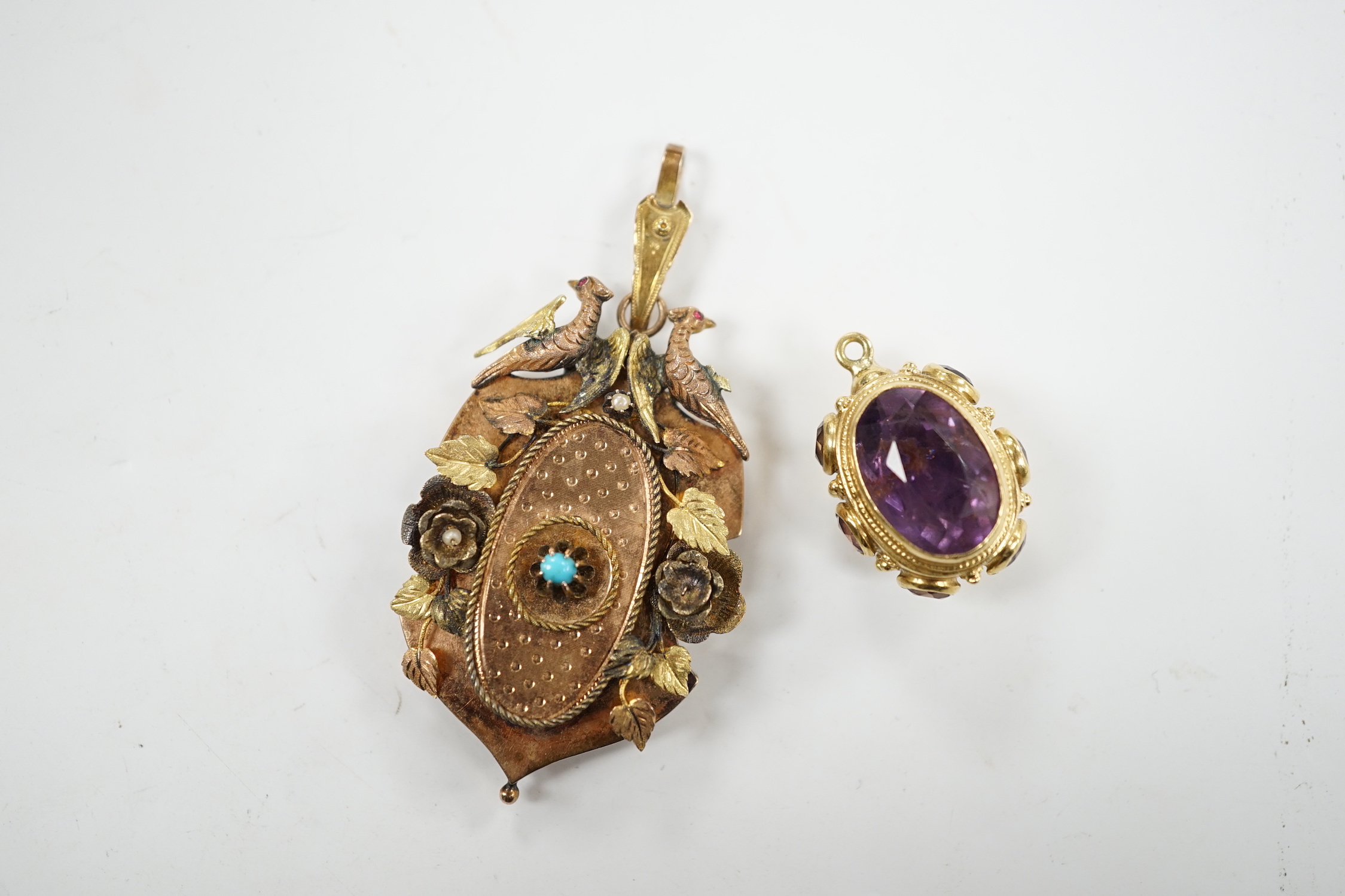 A Victorian three colour yellow metal, turquoise and seed pearl set pendant, decorated with birds and foliage, with glazed back, overall 65mm, together with a yellow metal and eight stone amethyst set charm.